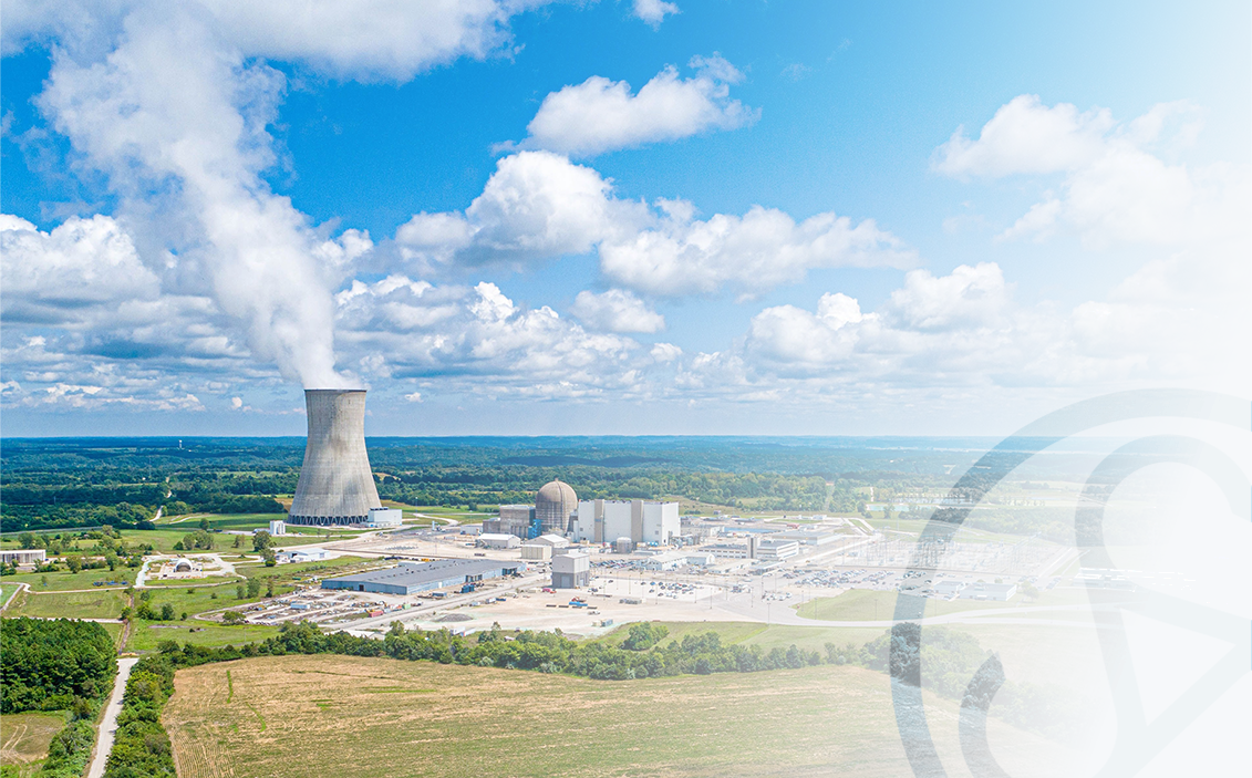 Aerial view of a nuclear power generating station with a cooling tower, reactor buildings, and surrounding infrastructure.